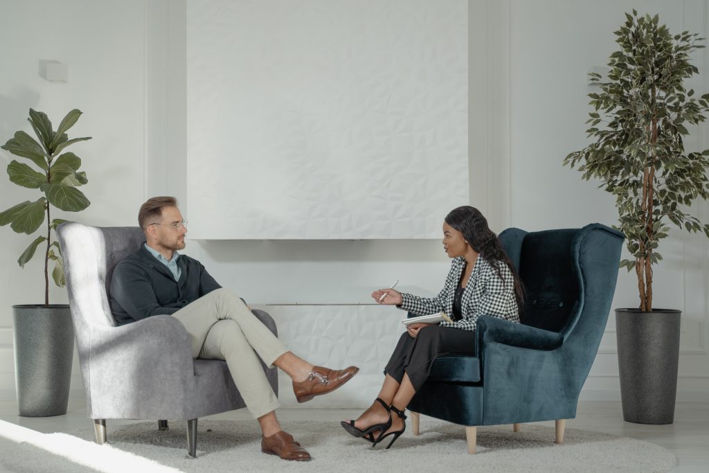 Une thérapeute et un client discutent, assis sur des fauteuils